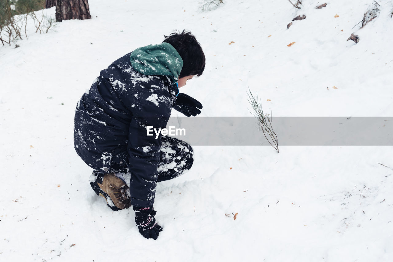 Full length of boy playing with snow in forest