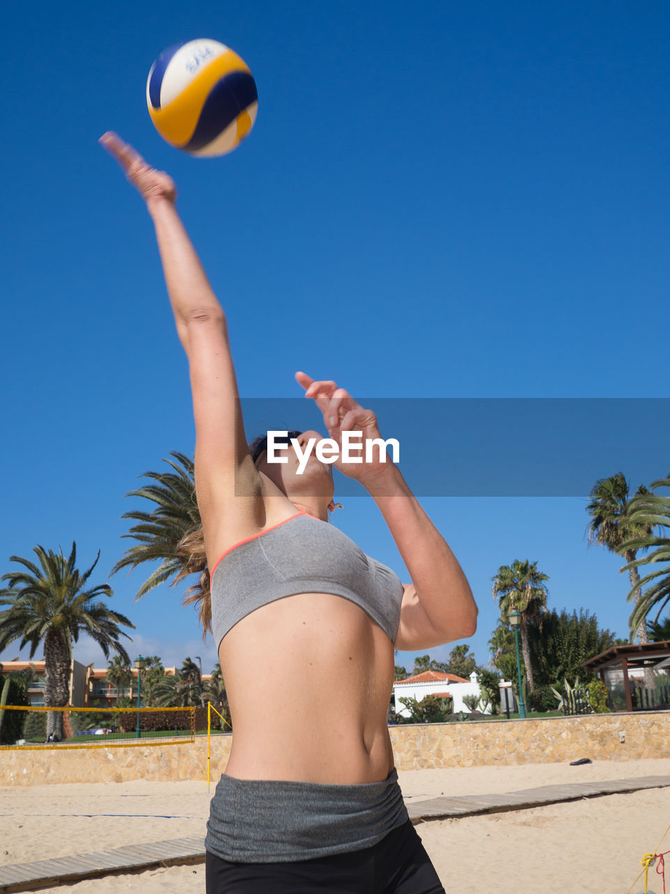 Woman playing volleyball at beach against sky