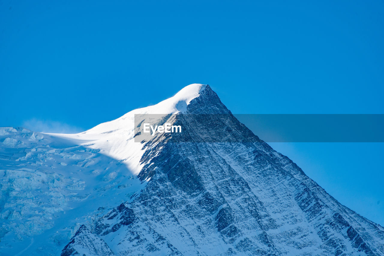 Scenic view of snowcapped mountains against clear blue sky