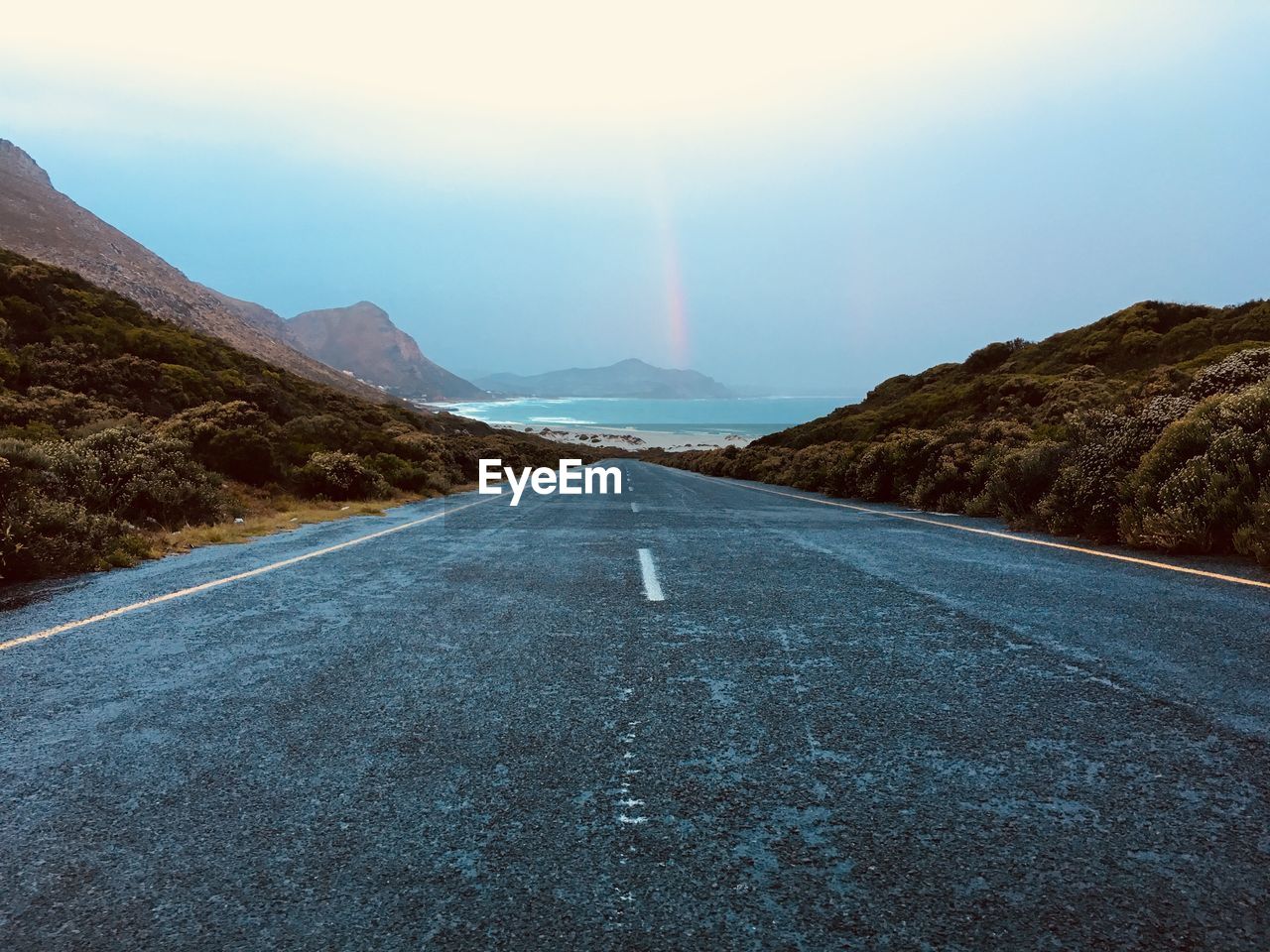 Diminishing perspective of road leading towards sea against sky