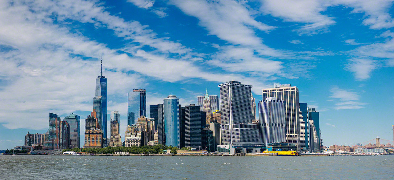 City at waterfront against cloudy sky