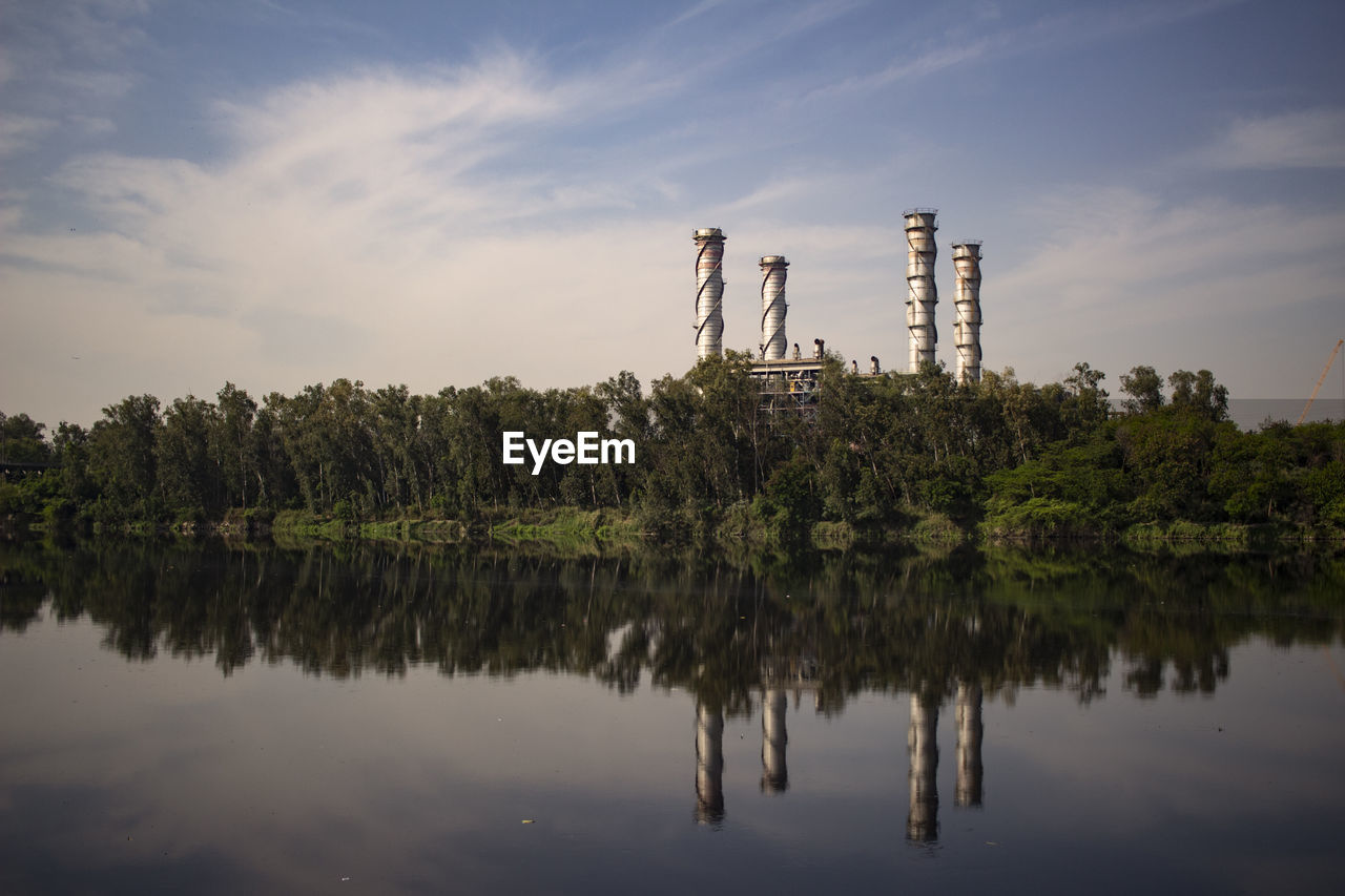 Industrial landscape beside a river body covered with trees