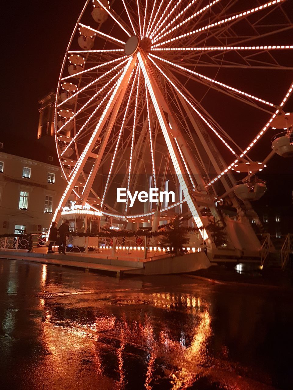 ILLUMINATED FERRIS WHEEL BY RIVER AT NIGHT