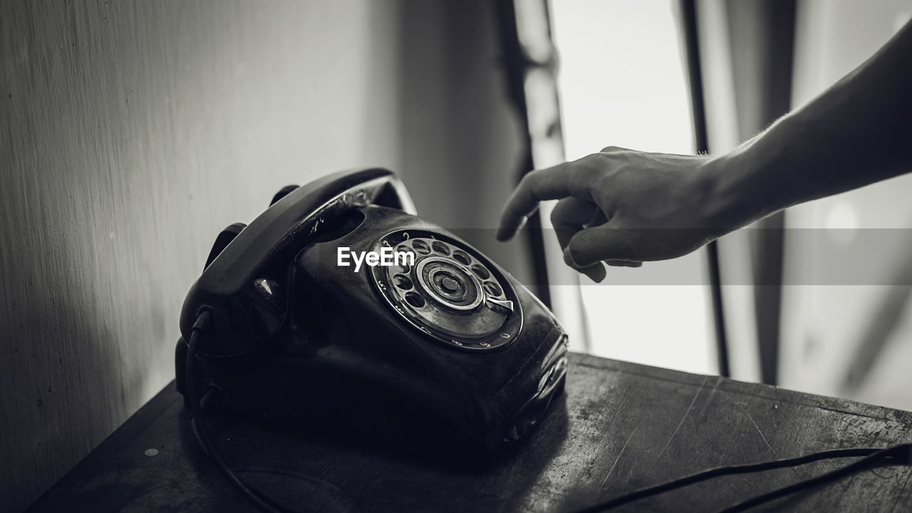 Cropped hand using rotary phone at table