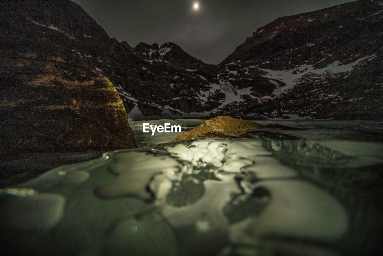 Close-up of river against mountains at night