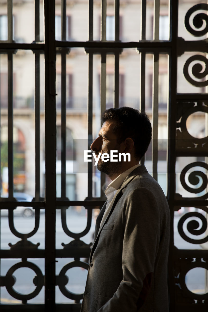 Businessman looking away while standing by gate