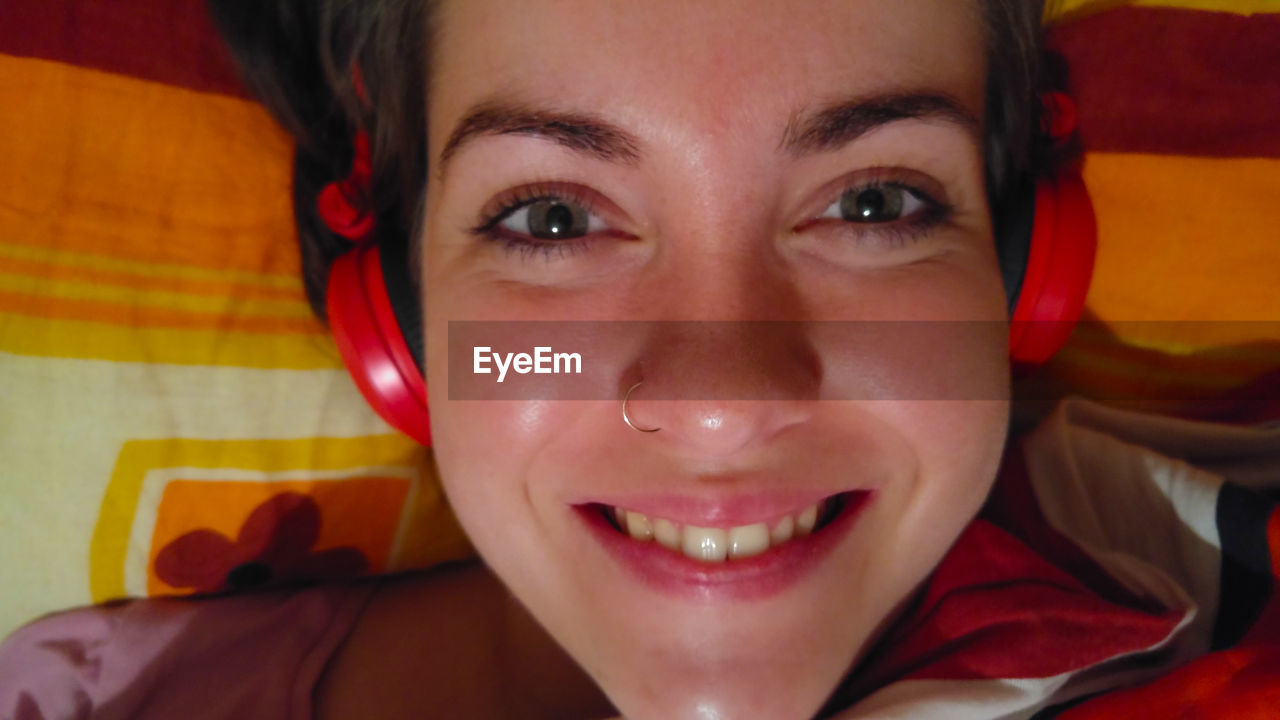 Directly above shot of woman listening music while lying on bed at home