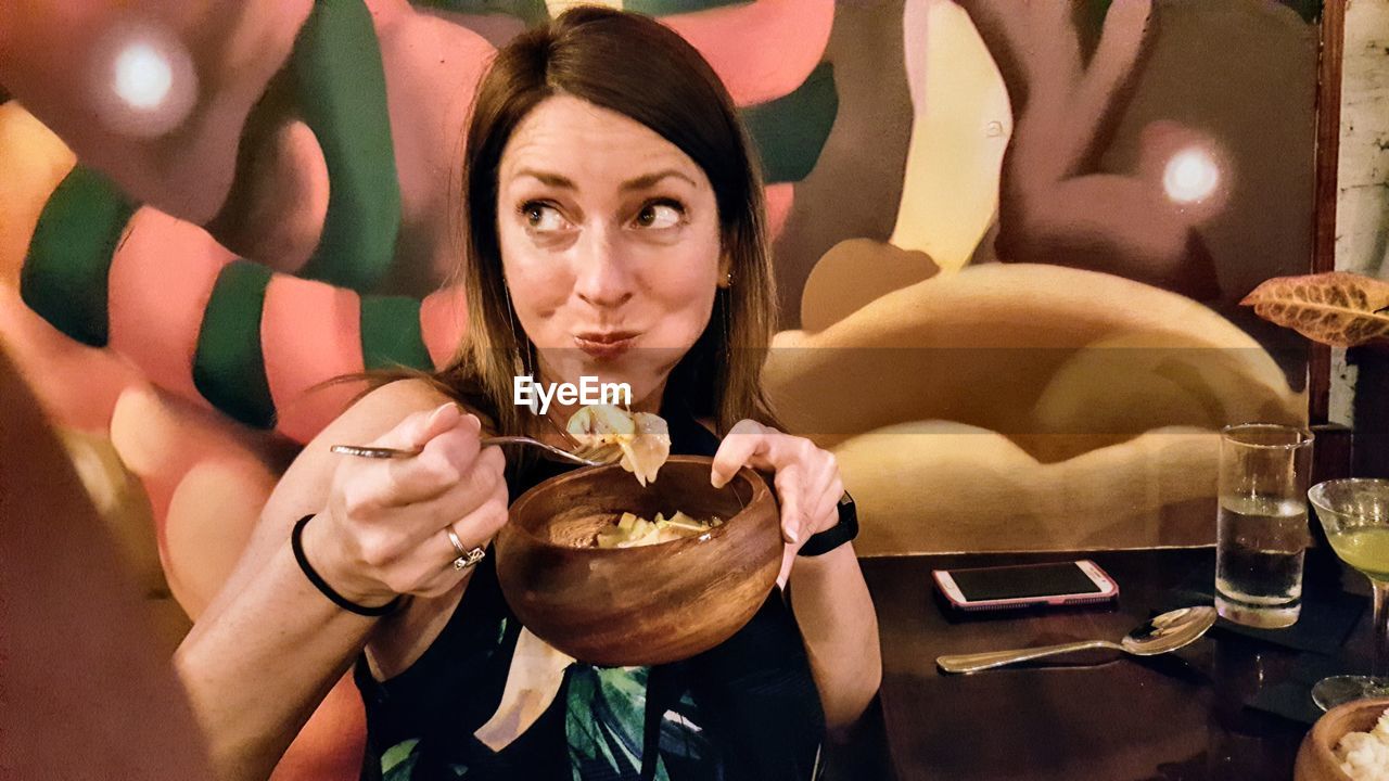 PORTRAIT OF YOUNG WOMAN HOLDING FOOD