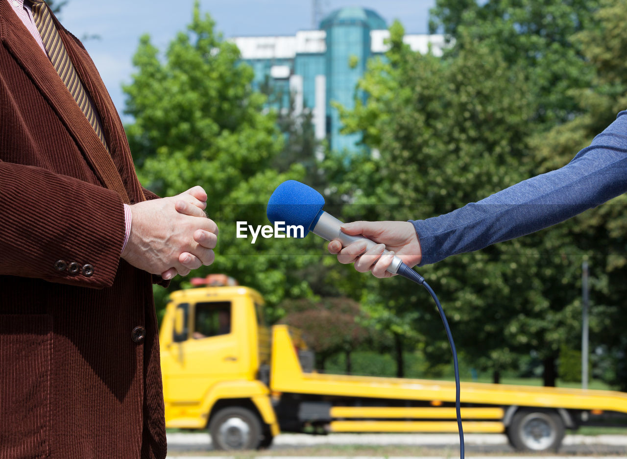 Cropped hand holding microphone by businessman during interview