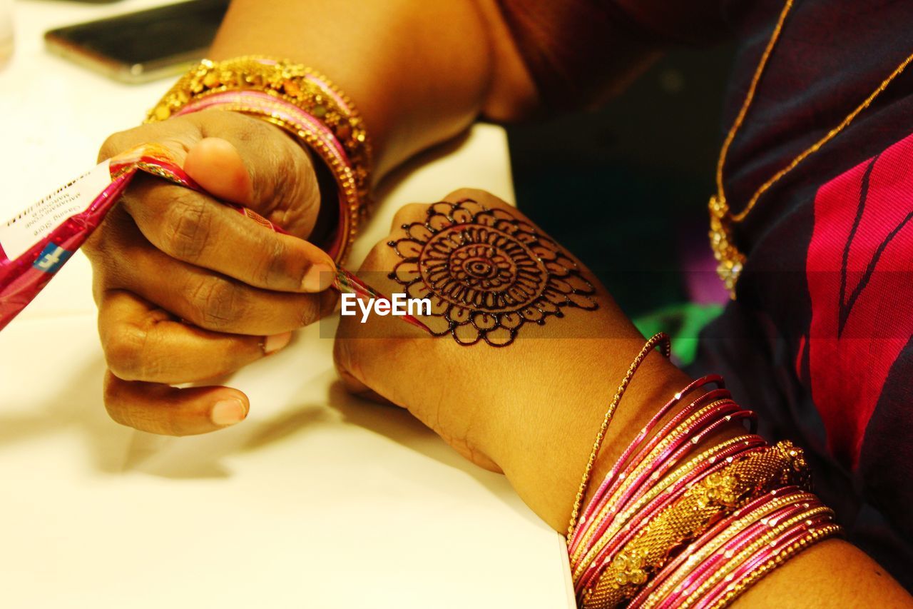 Close-up of woman making henna tattoo