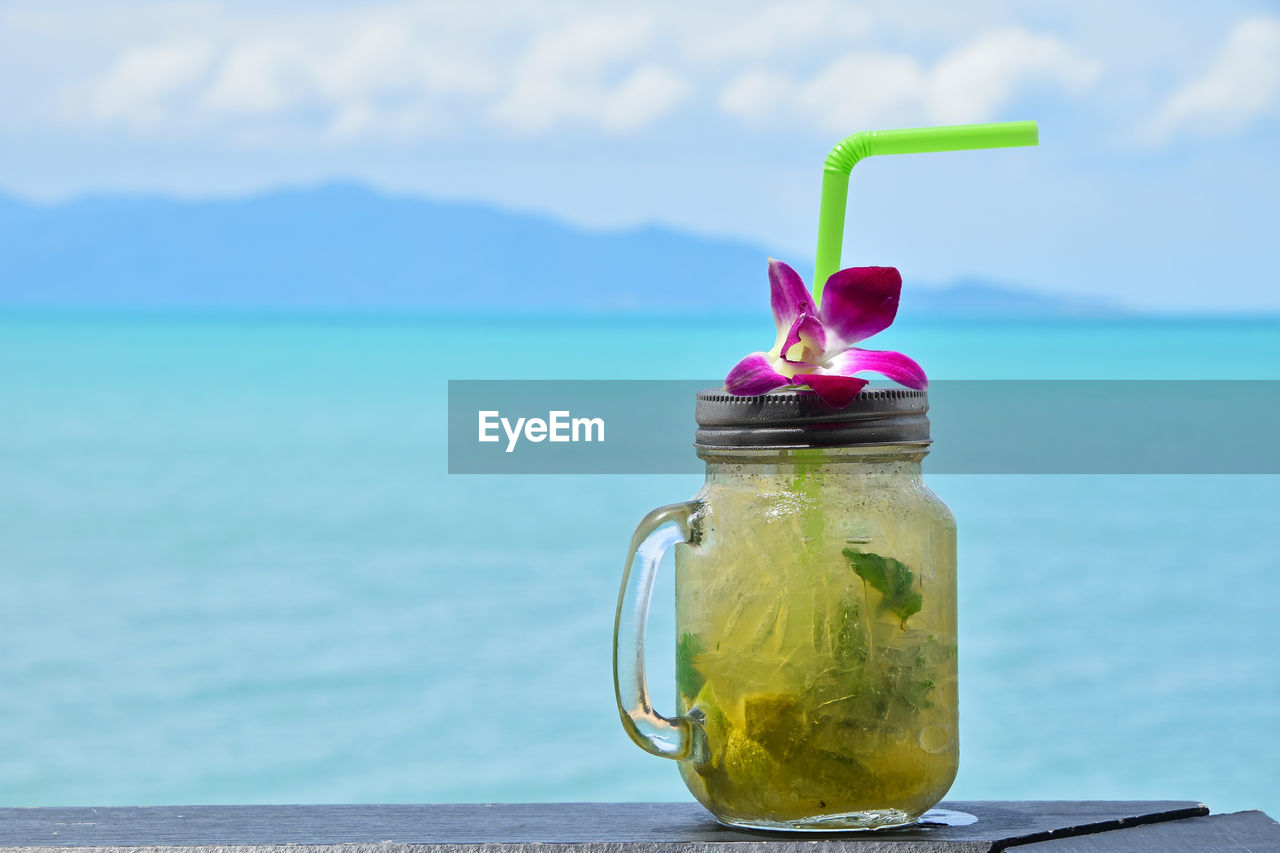 Close-up of fresh mojito in glass jar on table against sea