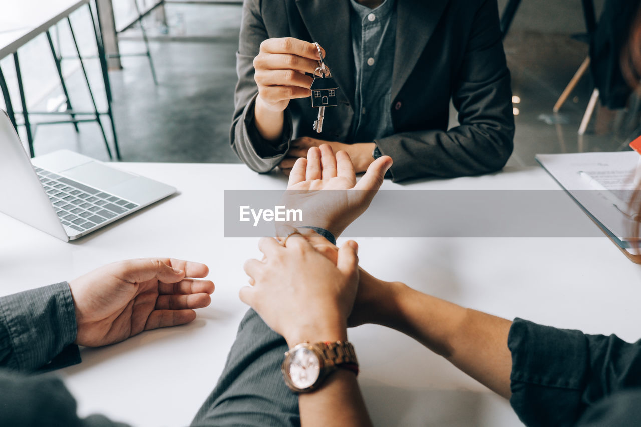 High angle view of real estate agent giving keys to customer on table