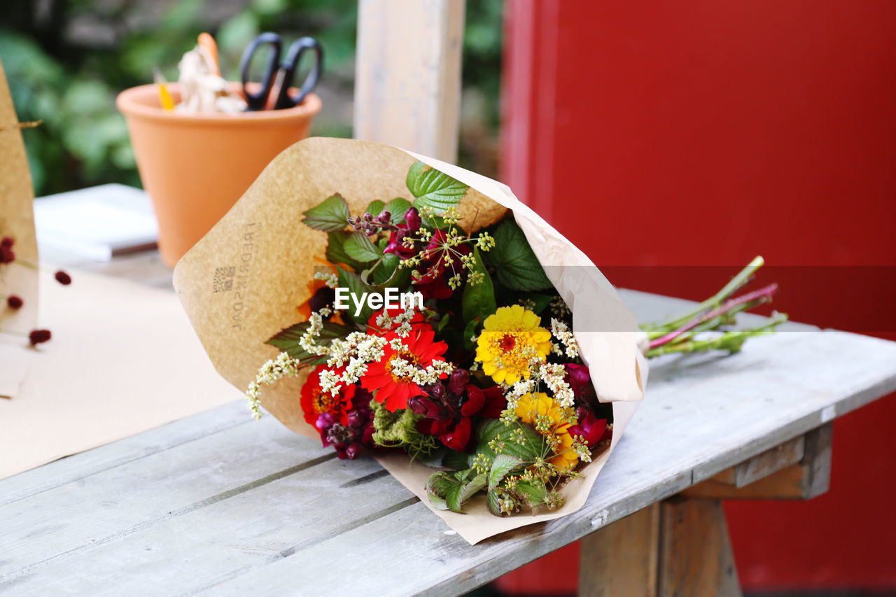 Bouquet of fresh flowers wrapped in paper on a florists workspace 