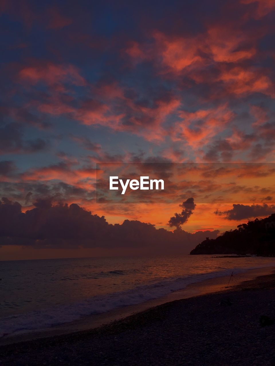 Scenic view of sea against dramatic sky during sunset