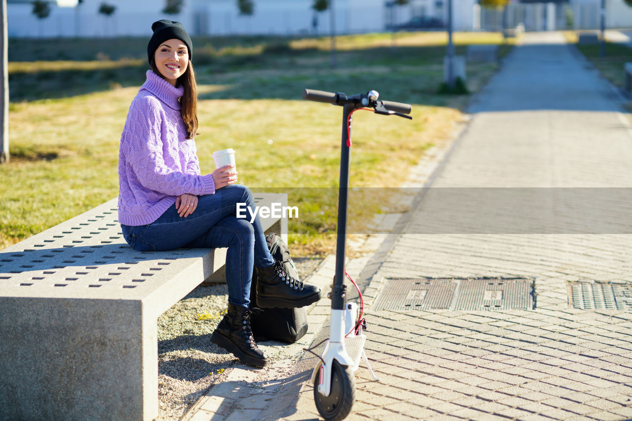 YOUNG WOMAN SITTING ON BENCH IN PARK