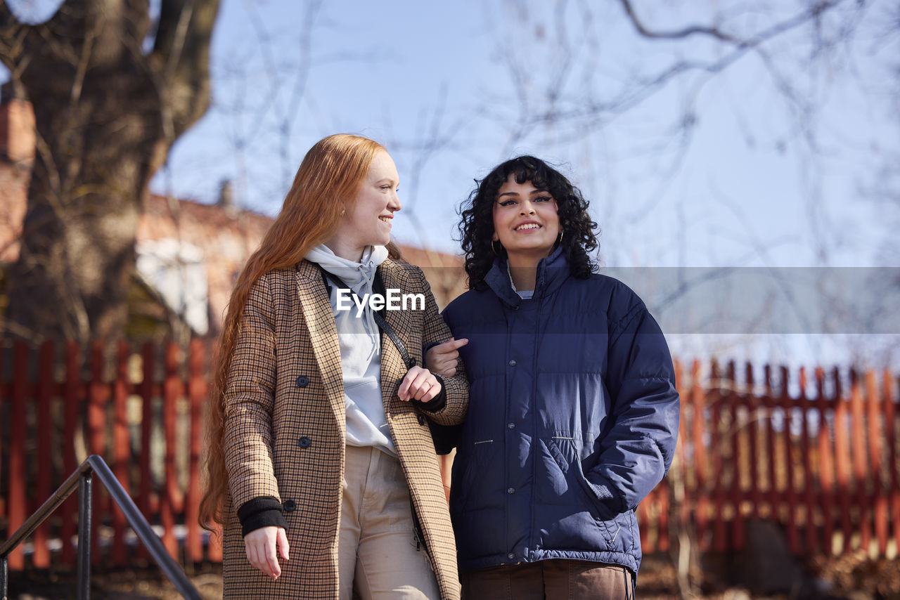 Smiling female friends walking in park