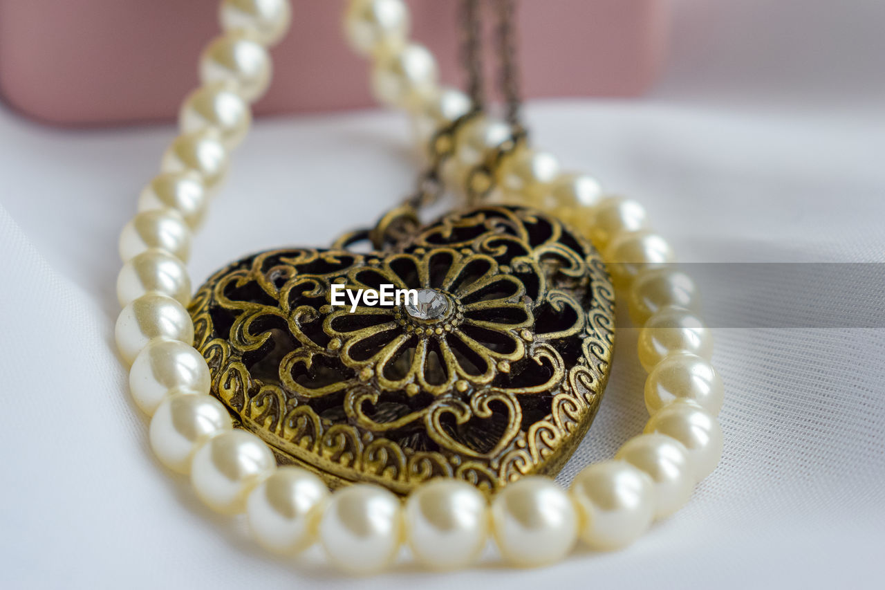 jewelry, jewellery, necklace, luxury, wealth, gold, close-up, pearl jewelry, fashion accessory, fashion, elegance, no people, indoors, pearl, gemstone, locket, yellow, metal, bracelet, diamond, pendant, precious gem, personal accessory, focus on foreground, ornate, studio shot, craft, earring