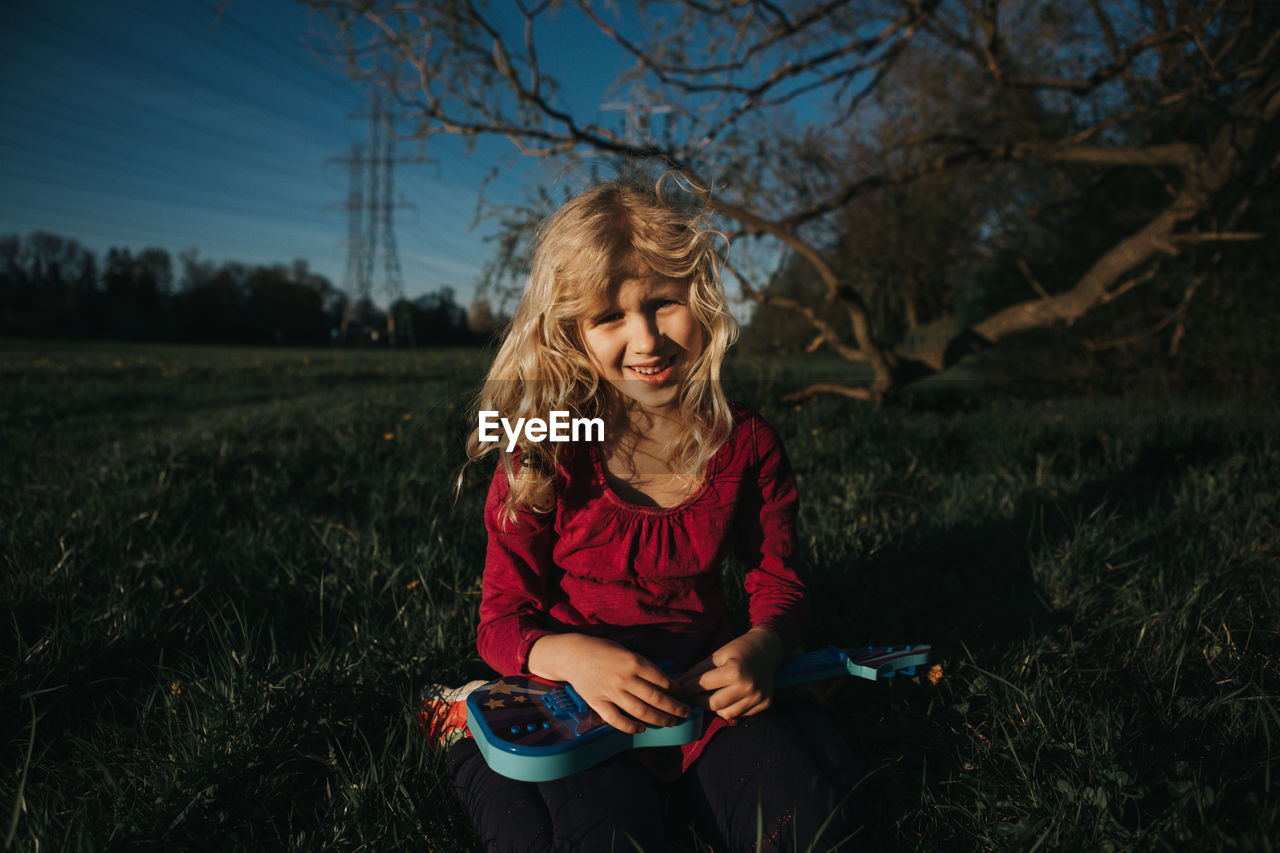 Girl playing with small guitar on field