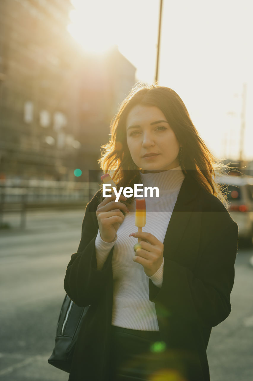 Portrait of beautiful woman holding flavored ice in city