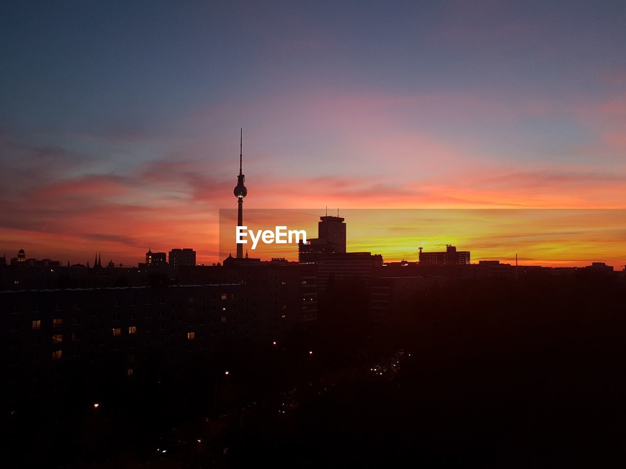 Silhouette of buildings against cloudy sky during sunset