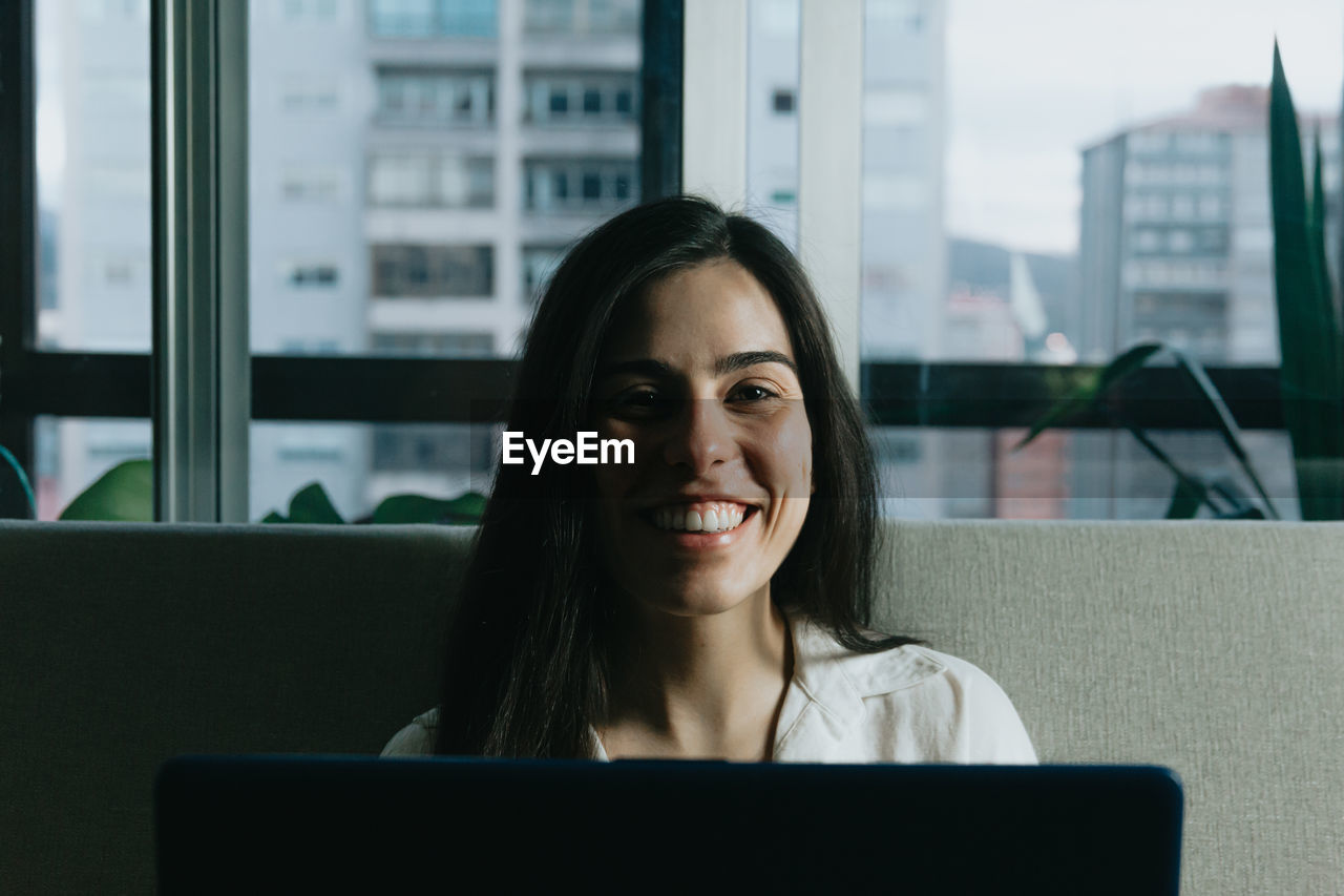 Portrait of smiling young businesswoman using laptop