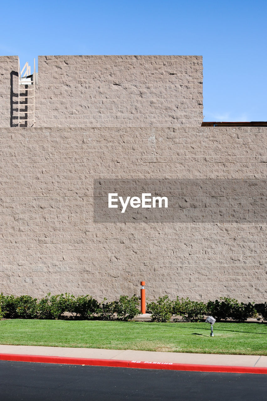 FULL LENGTH OF BOY ON WALL AGAINST BUILDING