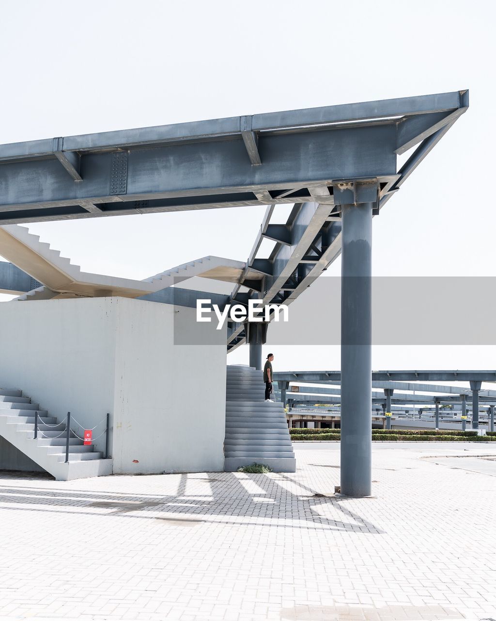 WOMAN WALKING BY BUILT STRUCTURE AGAINST SKY