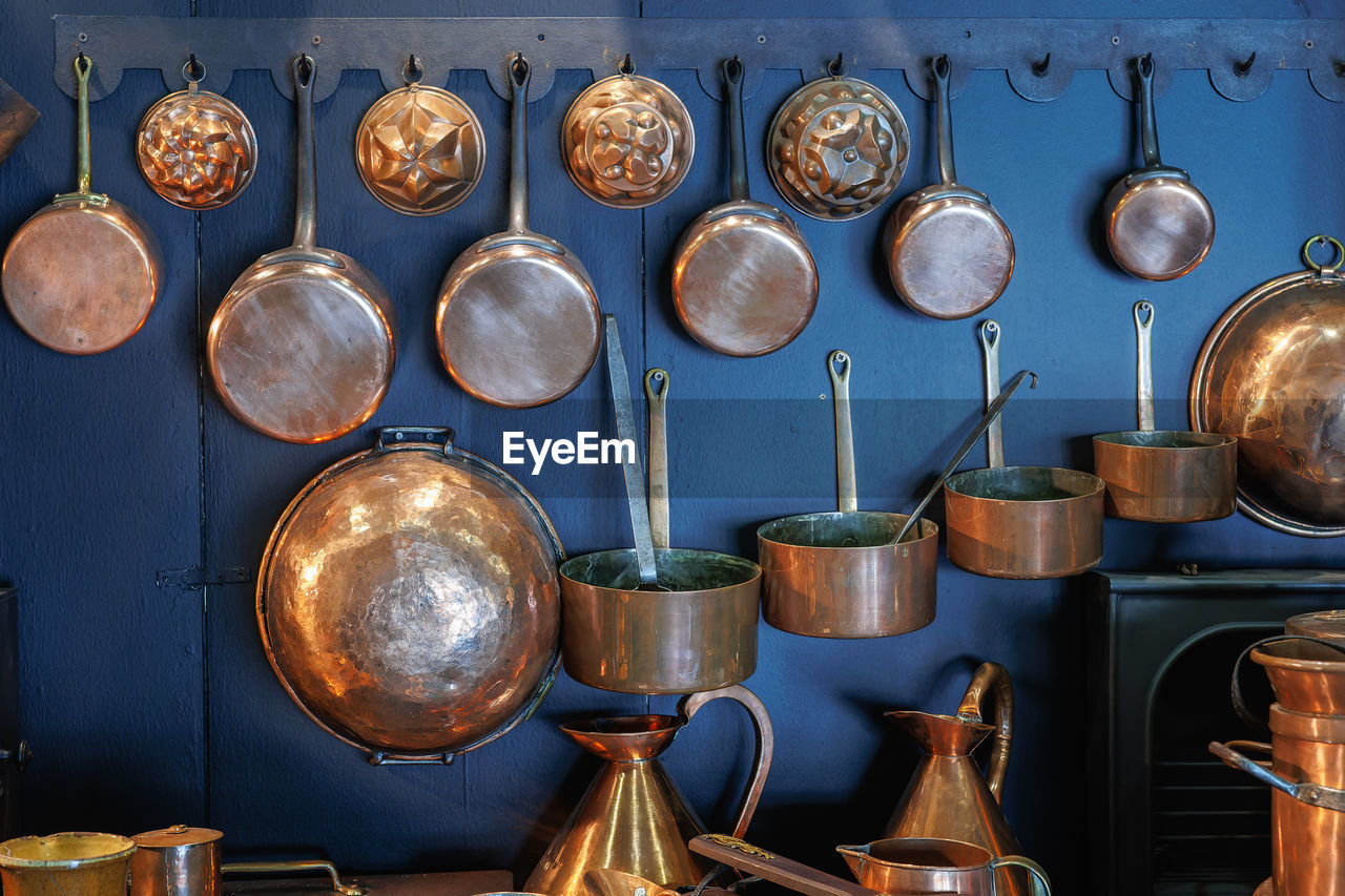 Copper pots and pans and other kitchen utensils in an antique metal kitchen.