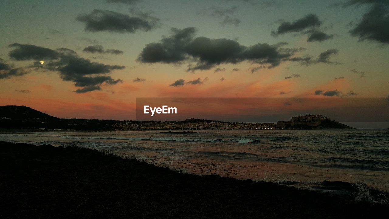 SCENIC VIEW OF BEACH AGAINST DRAMATIC SKY