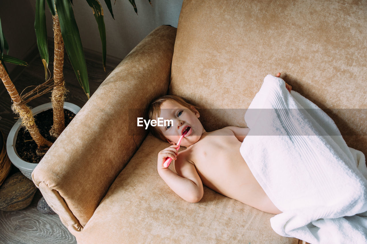 Cute child in big white towel. she brushes his teeth with toothbrush.