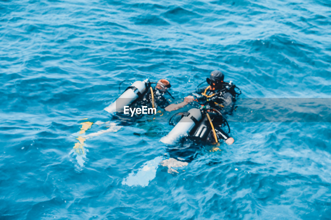 HIGH ANGLE VIEW OF PEOPLE FLOATING ON SEA