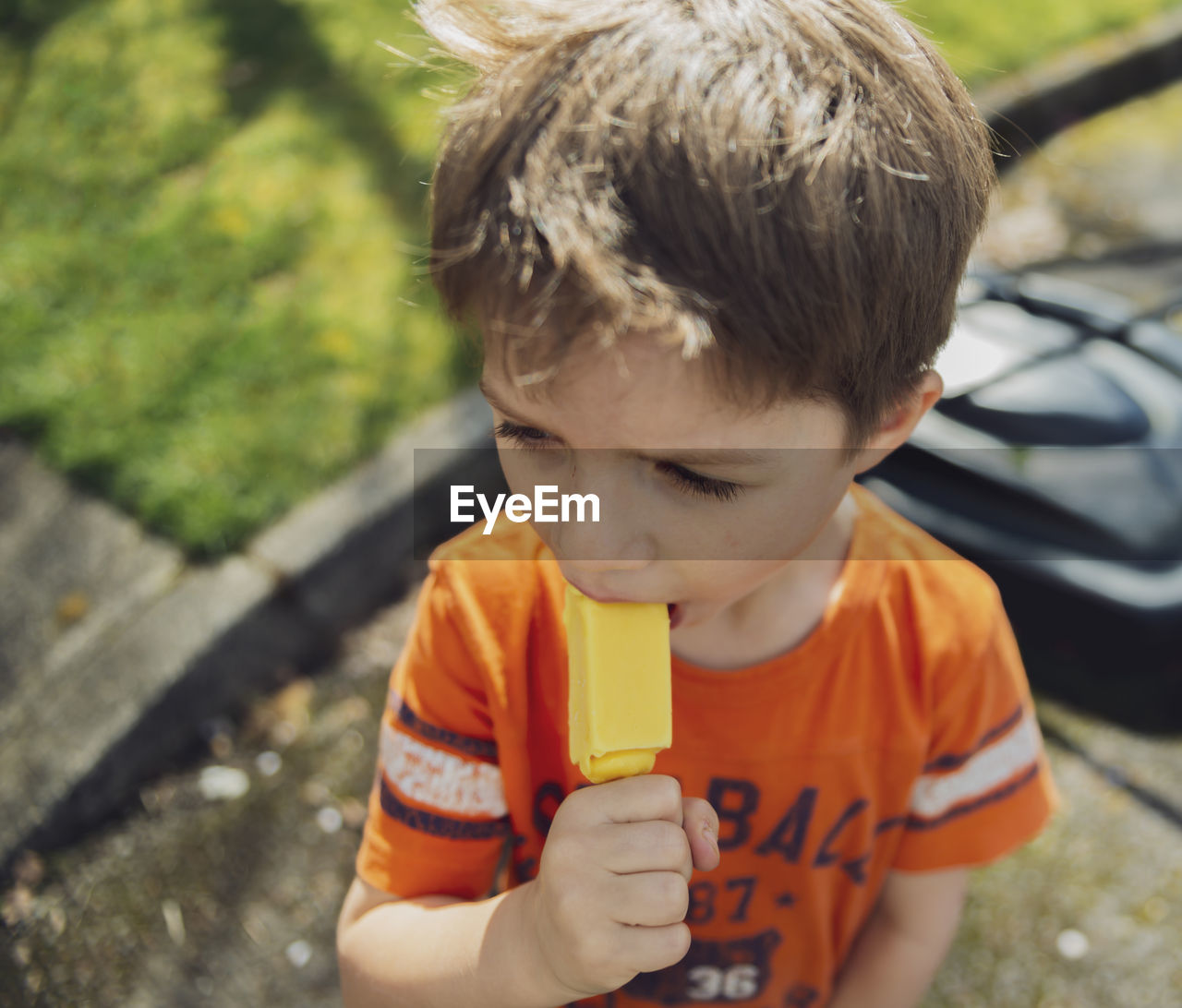 High angle view of boy eating popsicle while standing on road