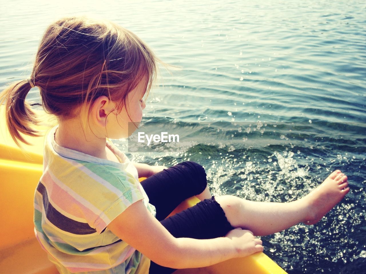 Full length of girl sitting in boat while splashing water