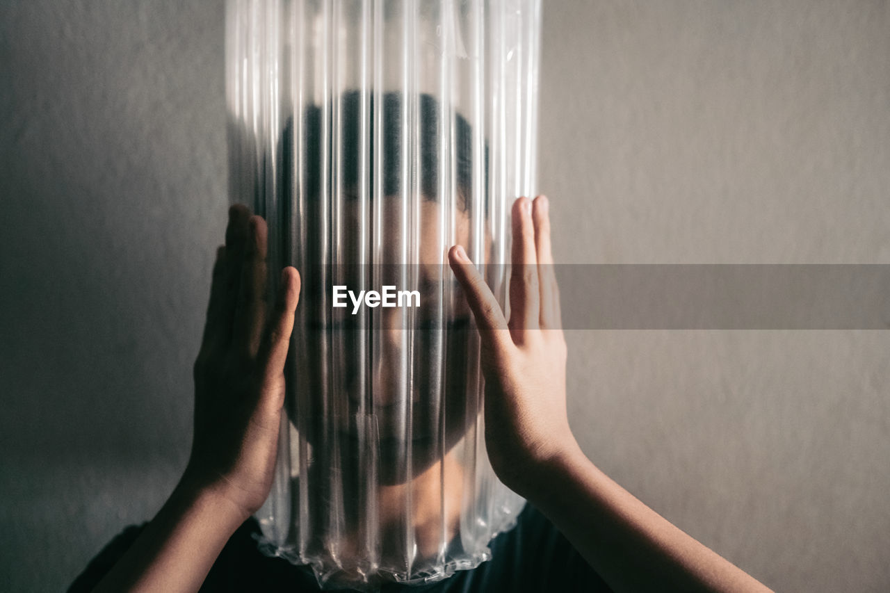 Boy wearing bubble wrap on face against wall