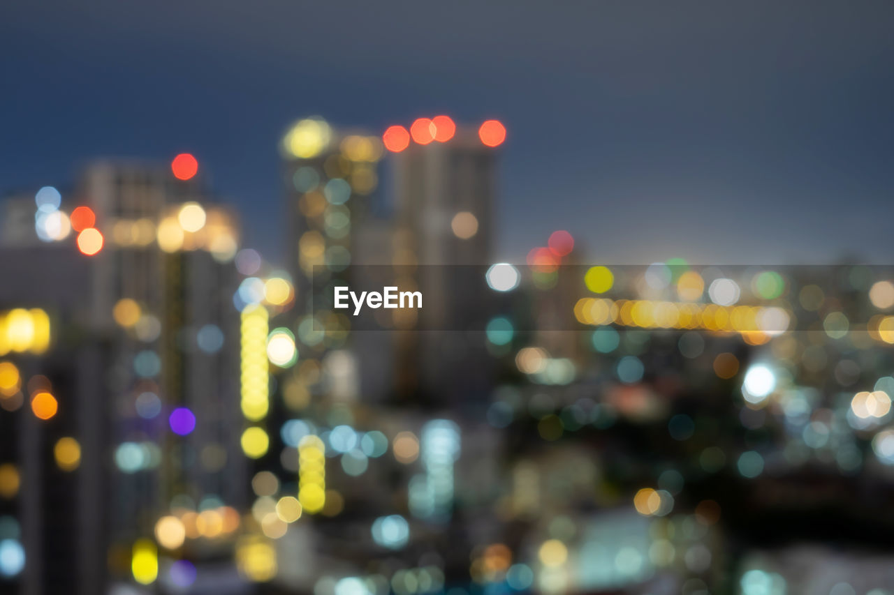 Defocused image of illuminated city against sky at night