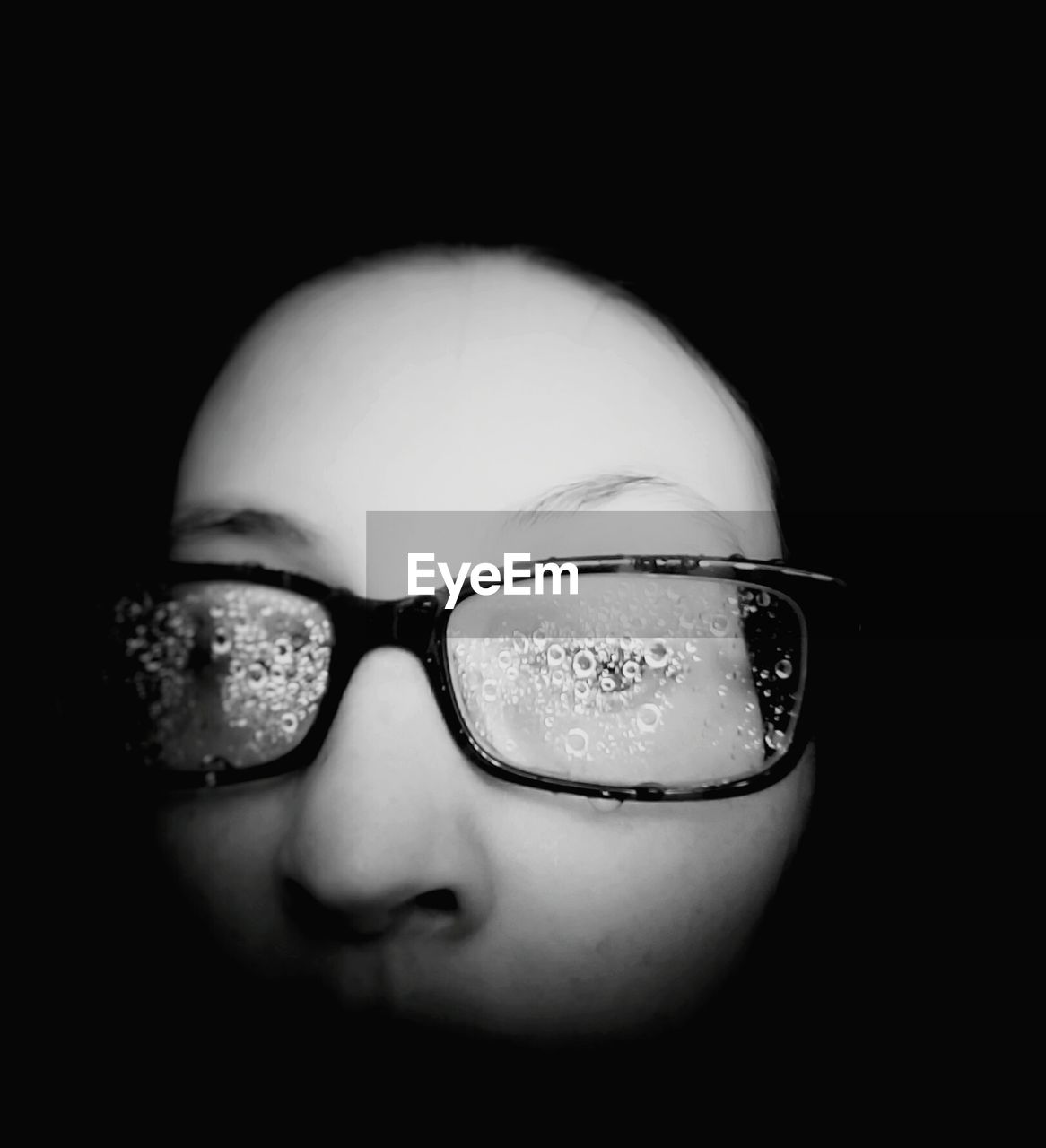 CLOSE-UP OF WOMAN WEARING EYEGLASSES AGAINST BLACK BACKGROUND