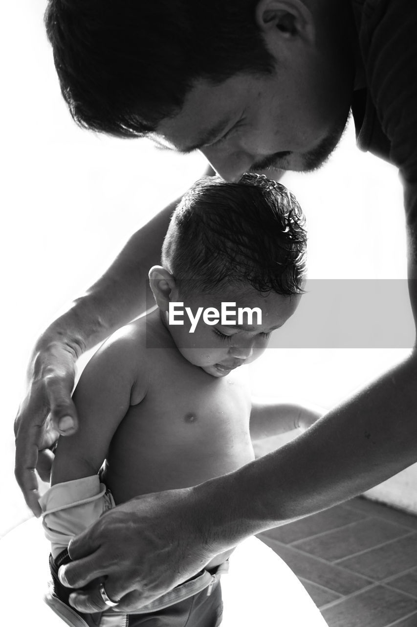 Man undressing son against white background