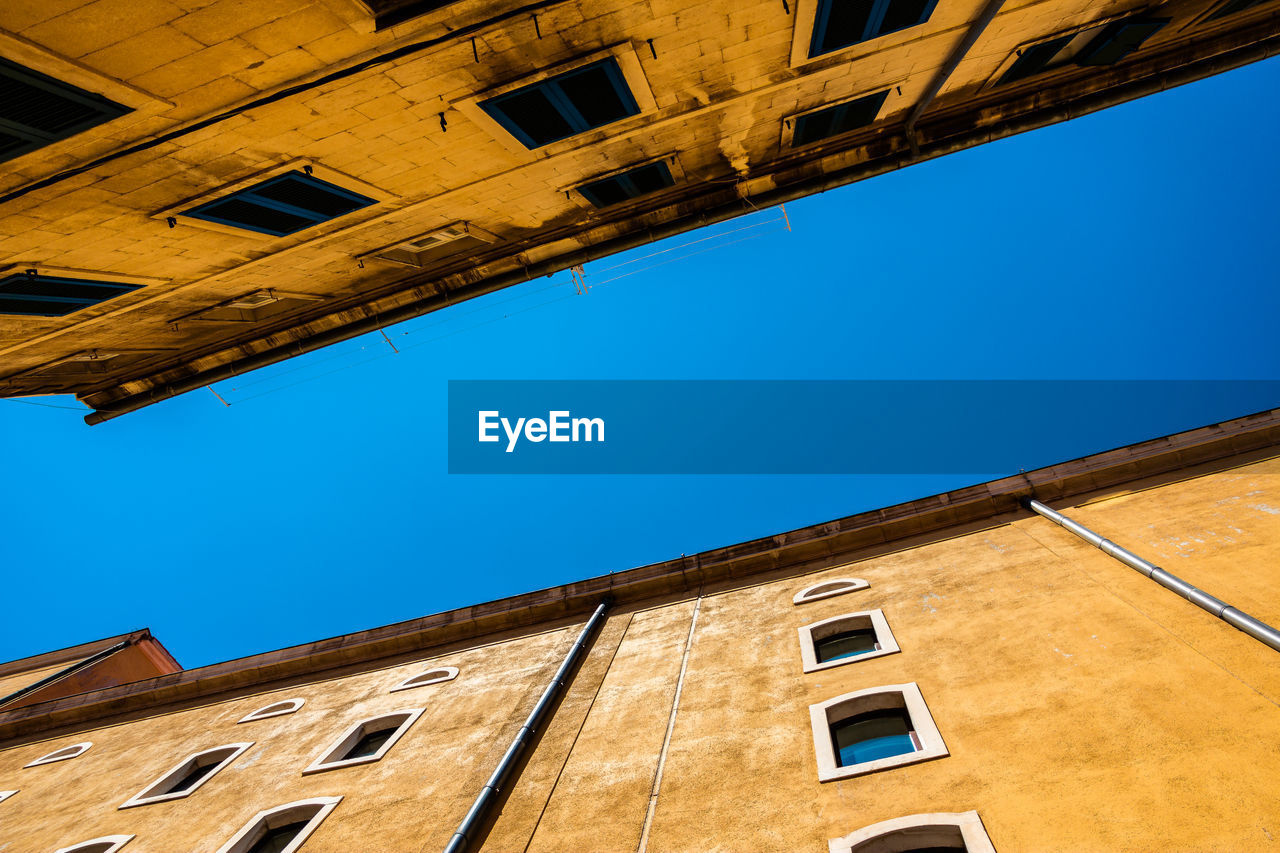 Low angle view of old building against clear blue sky