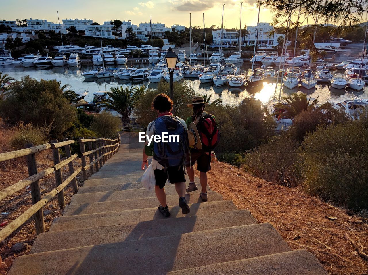 Rear view of backpack men walking on steps