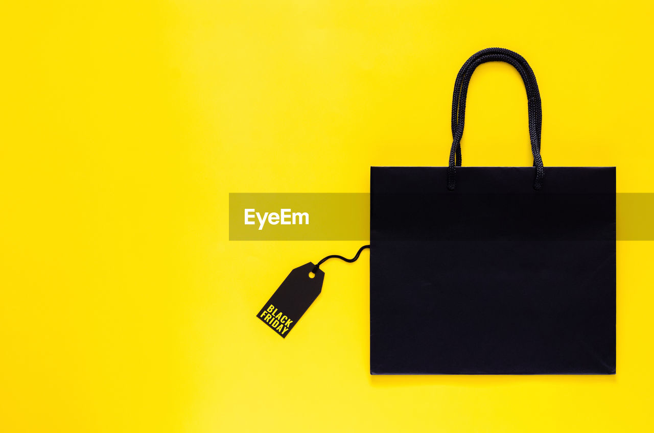 Shopping bag that have price tag with word on yellow background for black friday shopping concept.