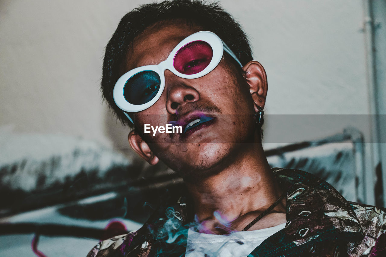 Portrait of young man wearing 3-d glasses while smoking cigarette