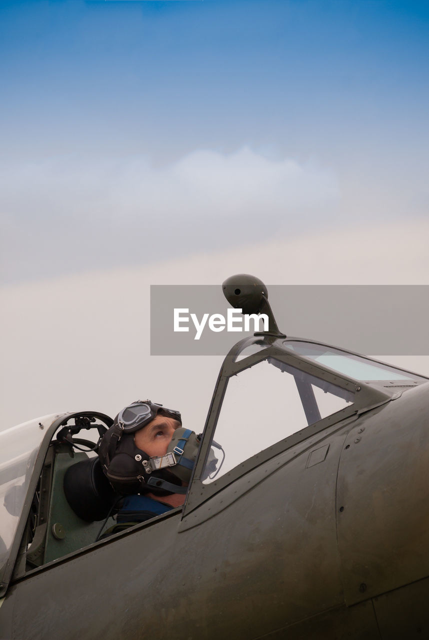 SIDE VIEW OF MAN WITH ARMS OUTSTRETCHED AGAINST SKY