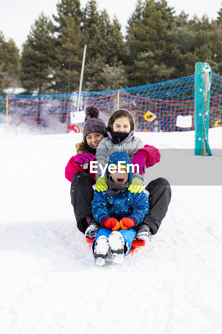 Portrait of family tobogganing on snow during winter