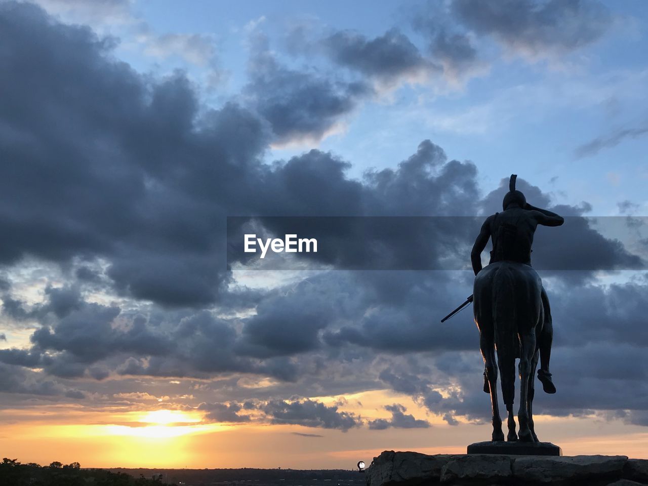 Statue of the scout against sky during sunset