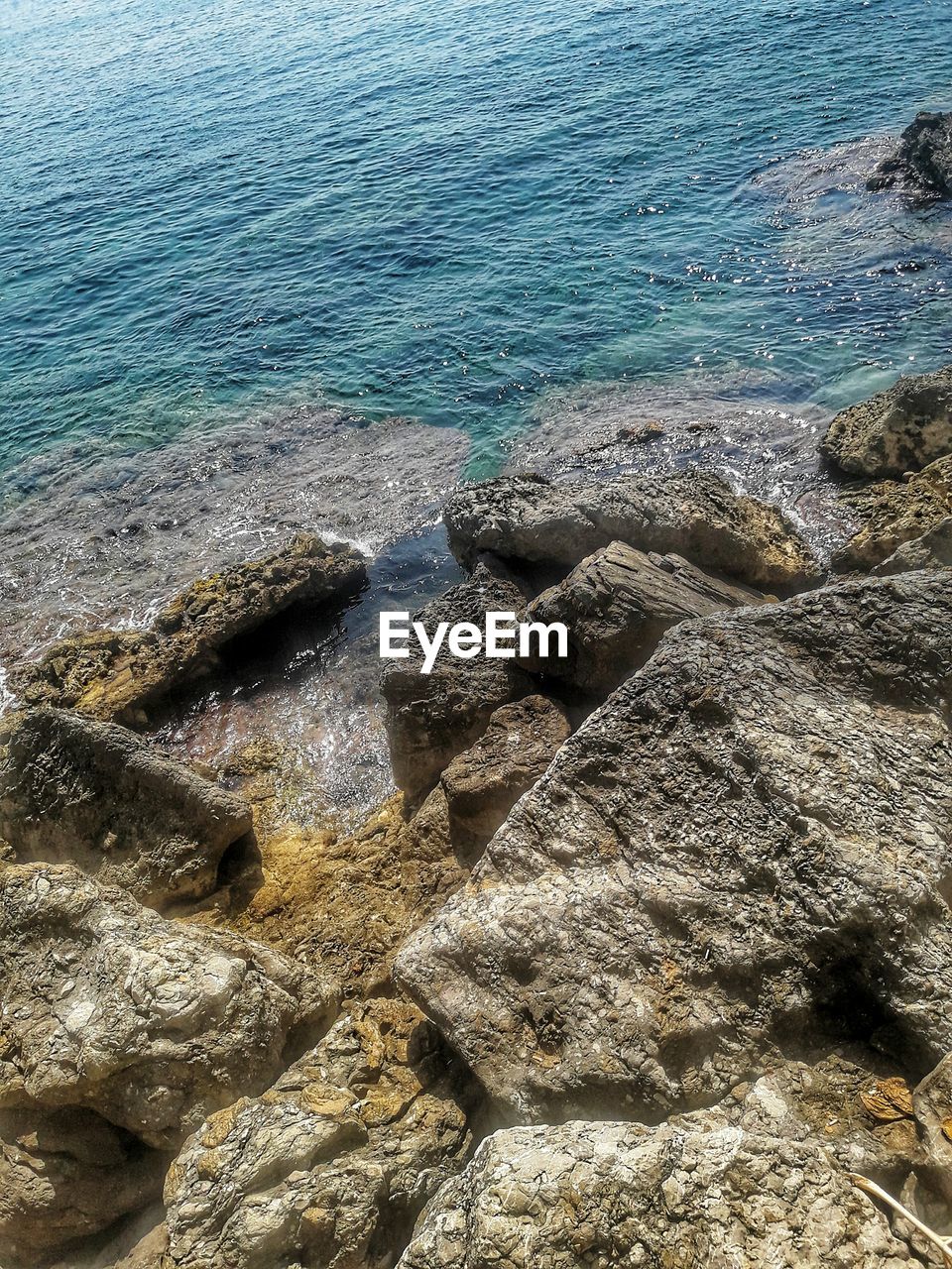 HIGH ANGLE VIEW OF ROCKS AT SEA SHORE