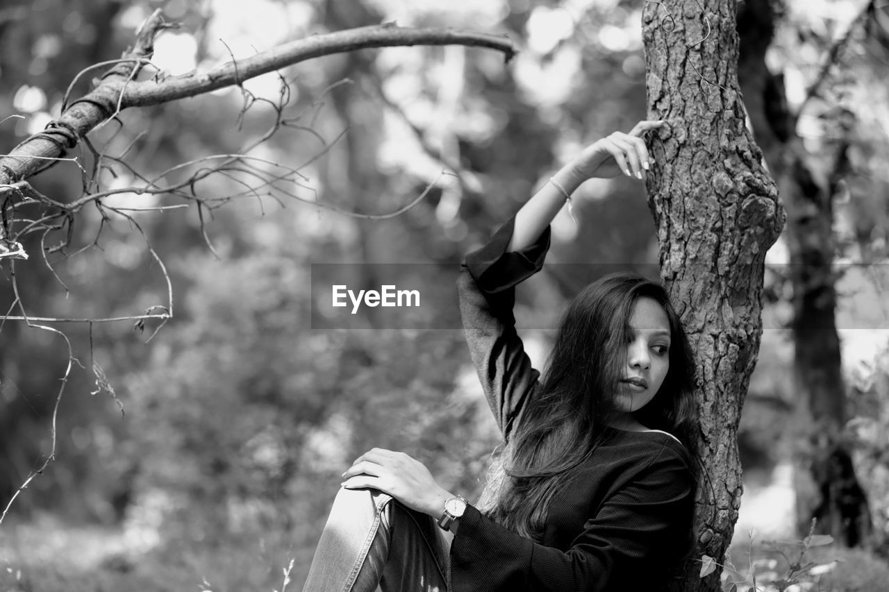 Portrait of woman with tree trunk in forest