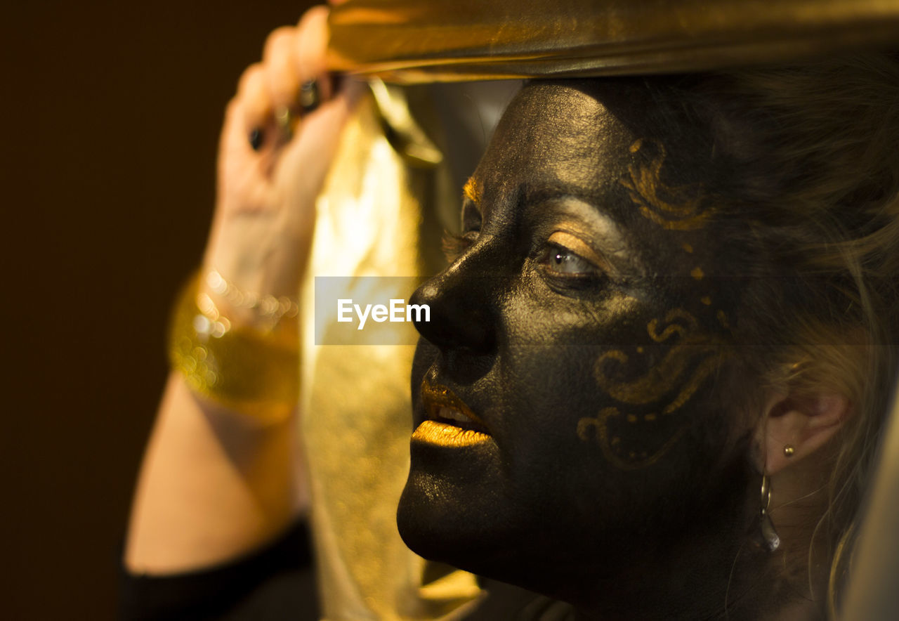 Portrait of a woman with black and gold make up, close up