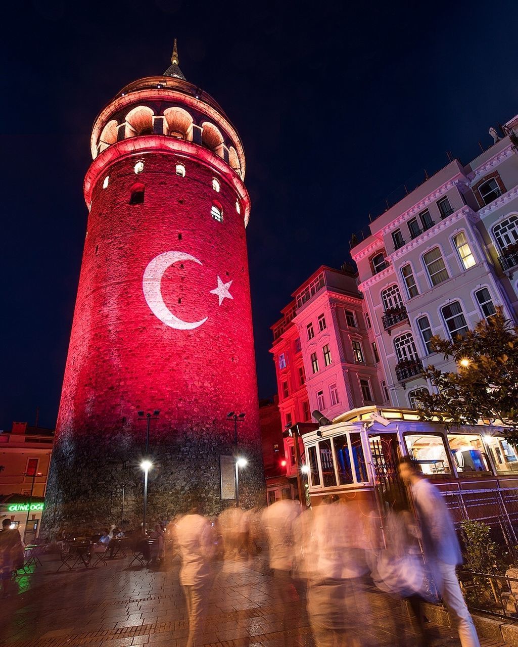 Blurred motion of people against turkish flag on tower at night