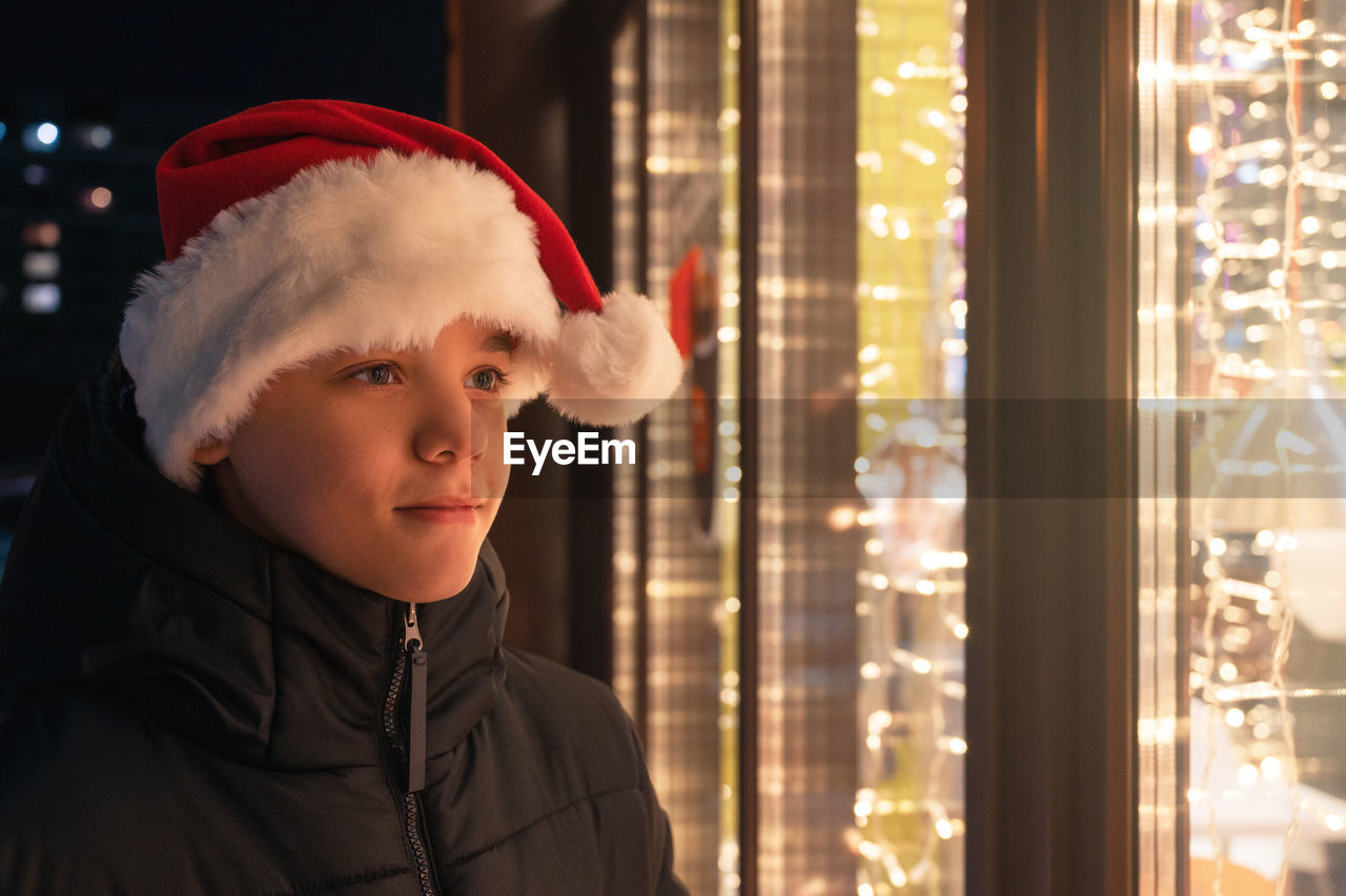 Smiling boy looking inside store from outdoors at night