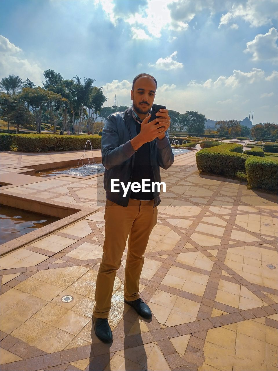 FULL LENGTH PORTRAIT OF YOUNG MAN STANDING ON MOBILE PHONE